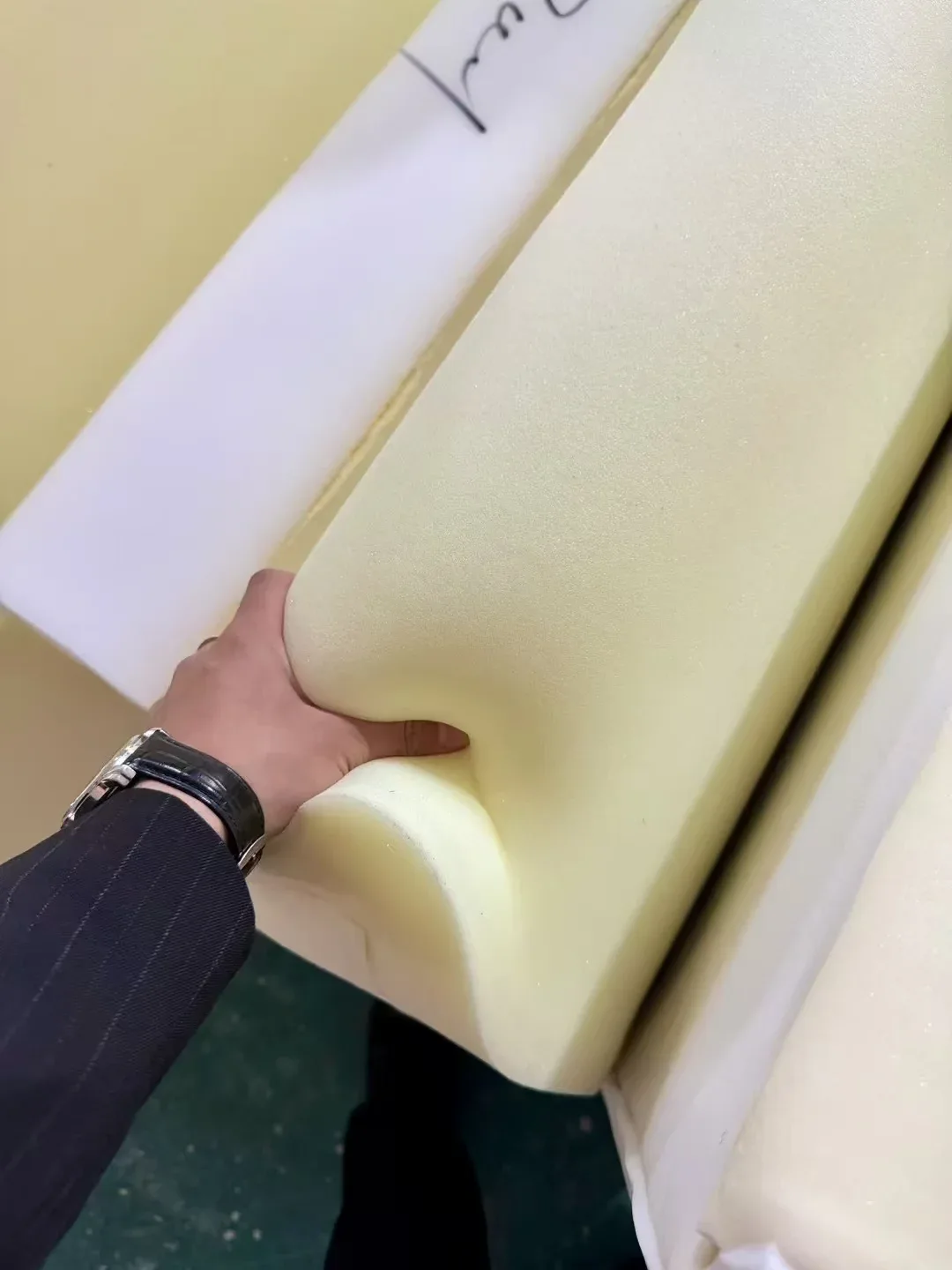 A hand pressing seat foam in the sofa maker's post. Softness cannot travel down a video link, so get the foam density in writing and compare it with.
