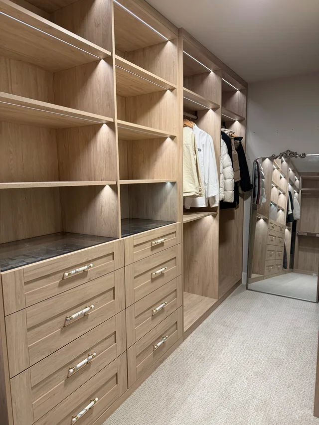 Completed custom closet with wood-finish cabinetry, back panels and integrated lighting