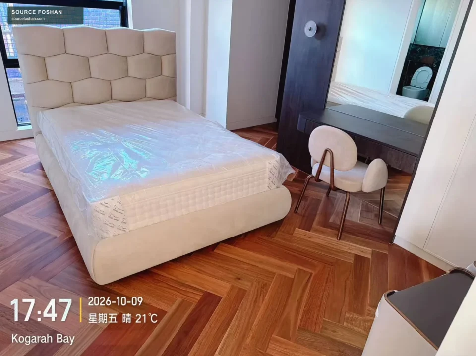 Upholstered bed frame and protected mattress in a Sydney-area bedroom