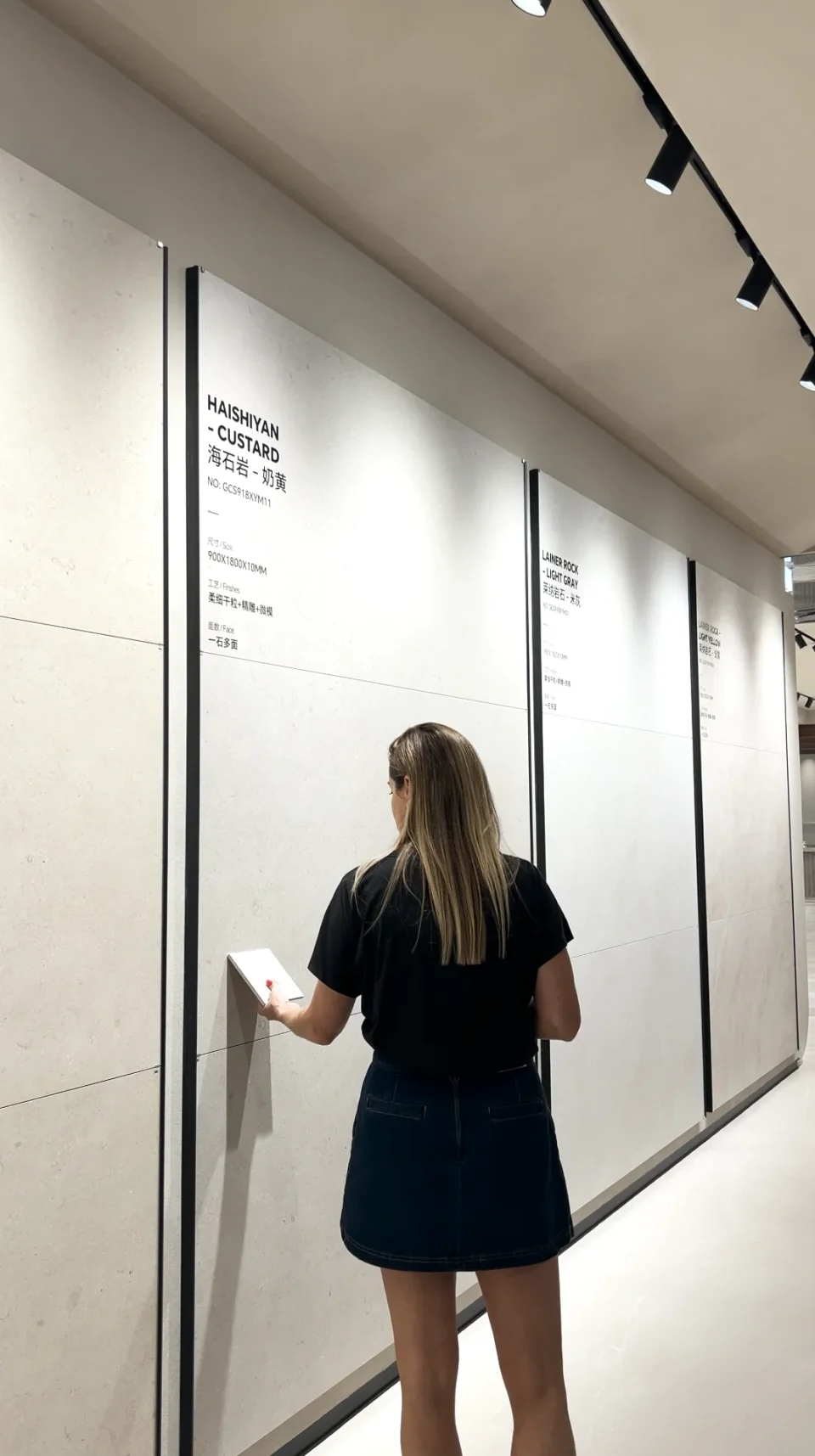 A buyer examining a large wall-tile display in a Foshan showroom.
