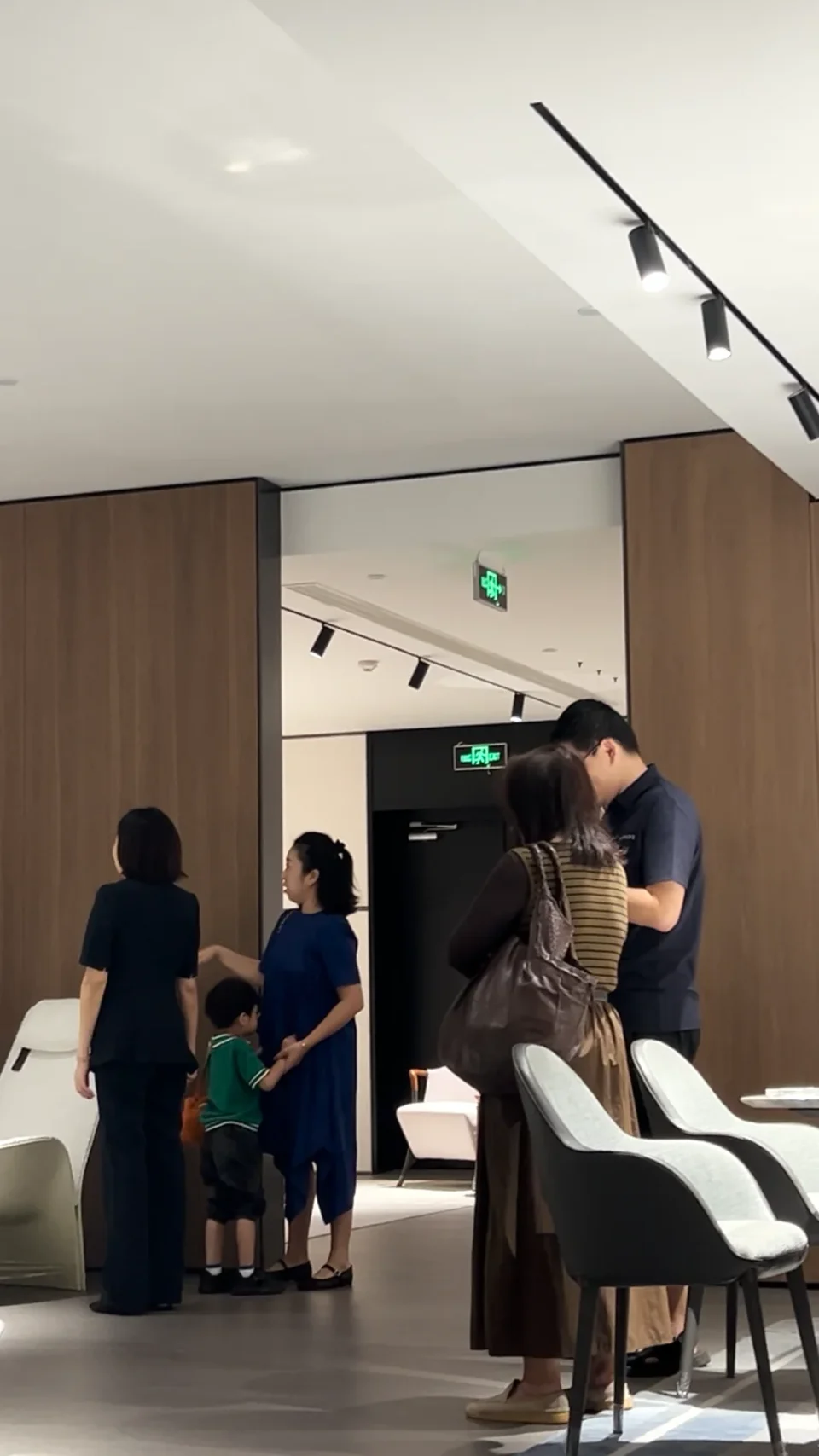 Visitors and a guide discussing furniture in a showroom.