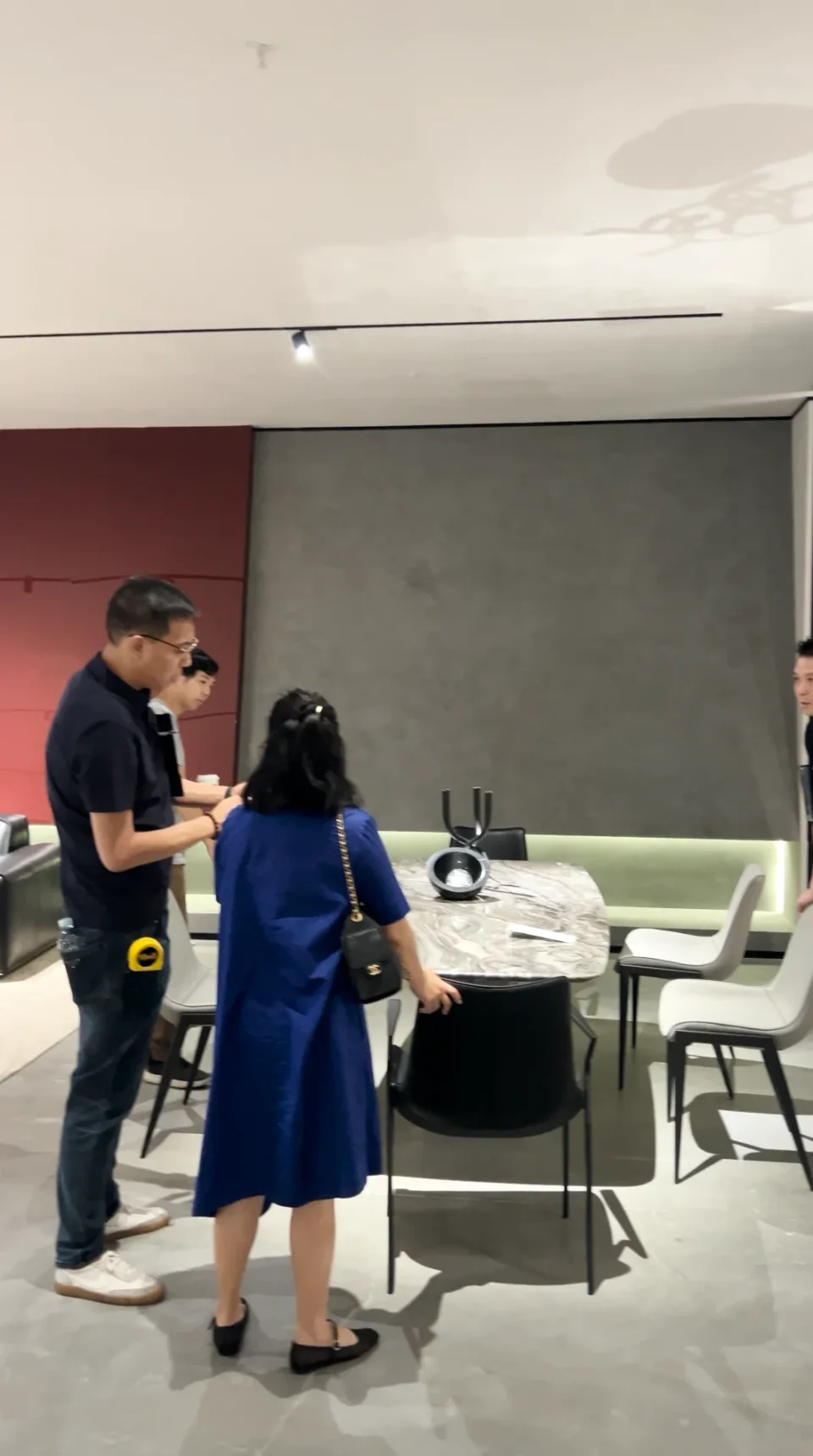 A guide and a visitor talking beside a dining table and chairs.