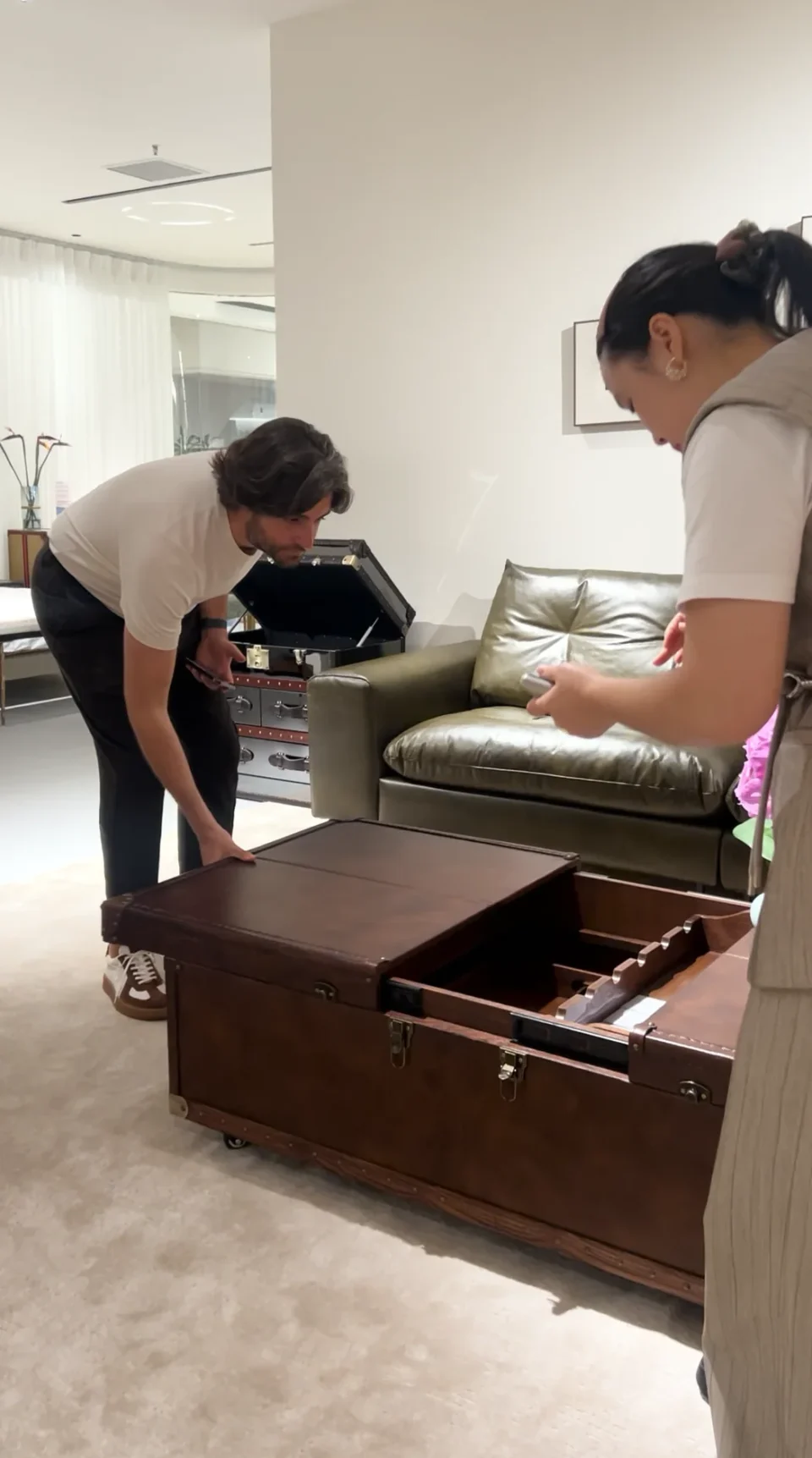 A buyer examining the open drawer of a wood-finish coffee table.
