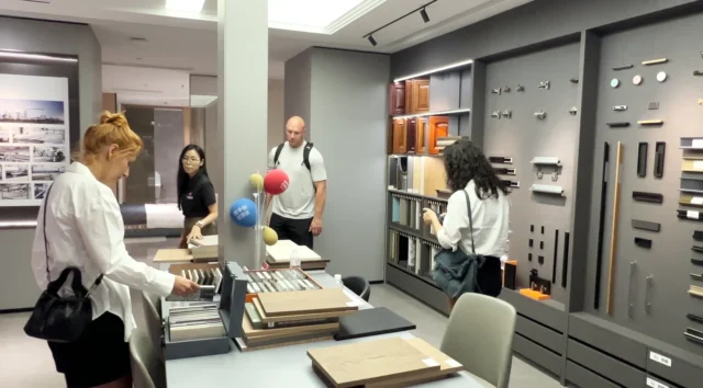 Visitors comparing cabinetry samples and hardware displays in a showroom.