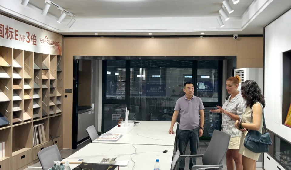 Visitors and staff in a cabinet supplier sample room with board displays and a worktable.