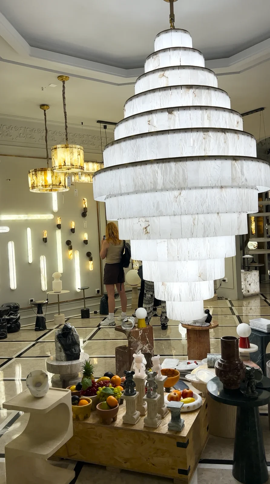 A large tiered chandelier displayed among other lights in a showroom.