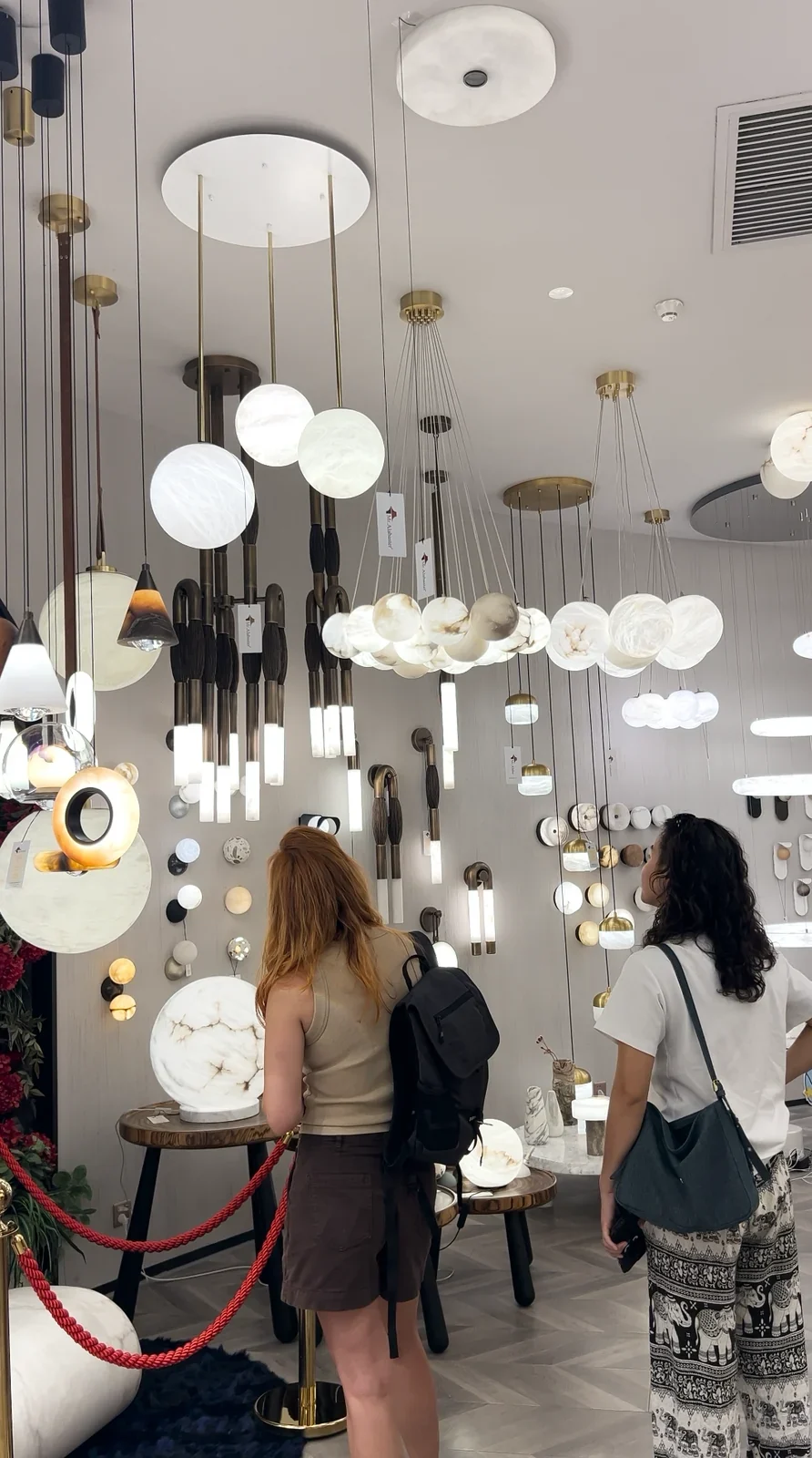 Visitors browsing pendant lights and wall lights in a lighting showroom.