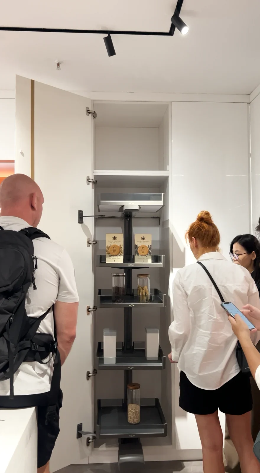 An open tall cabinet showing pull-out pantry storage in a showroom.